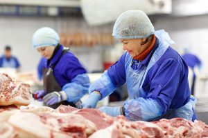 Two woman cutting into meat