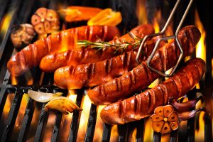 5 sausages being cooked over a grill