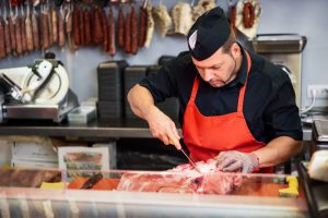 A butcher cutting off a piece of wholesale meat