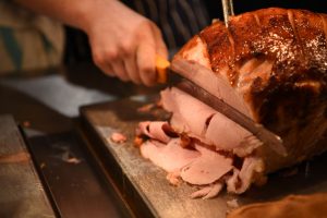 A butcher slicing off a piece of a Gammon Joint