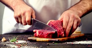 Close up of a man cutting a piece of meat